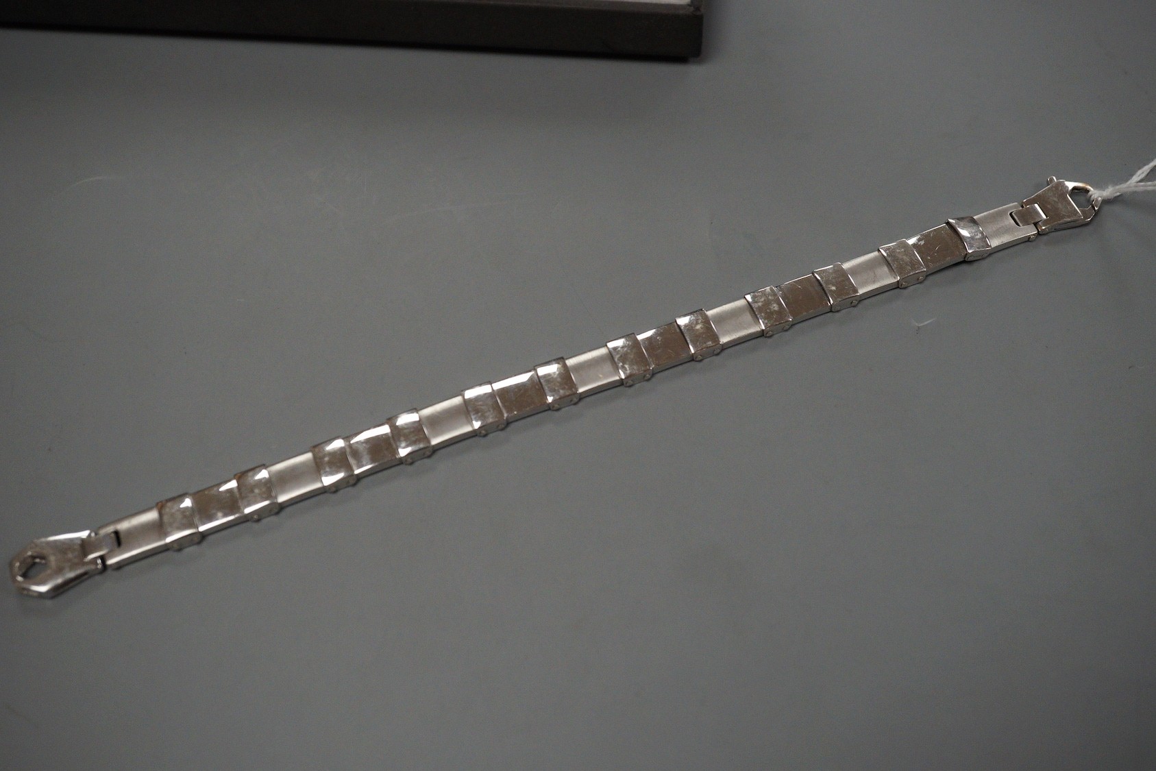 A cased modern white metal (tests as 18ct) bracelet with matt finish alternating links, overall 21.5cm, 34.7 grams, retailed by Musson.
